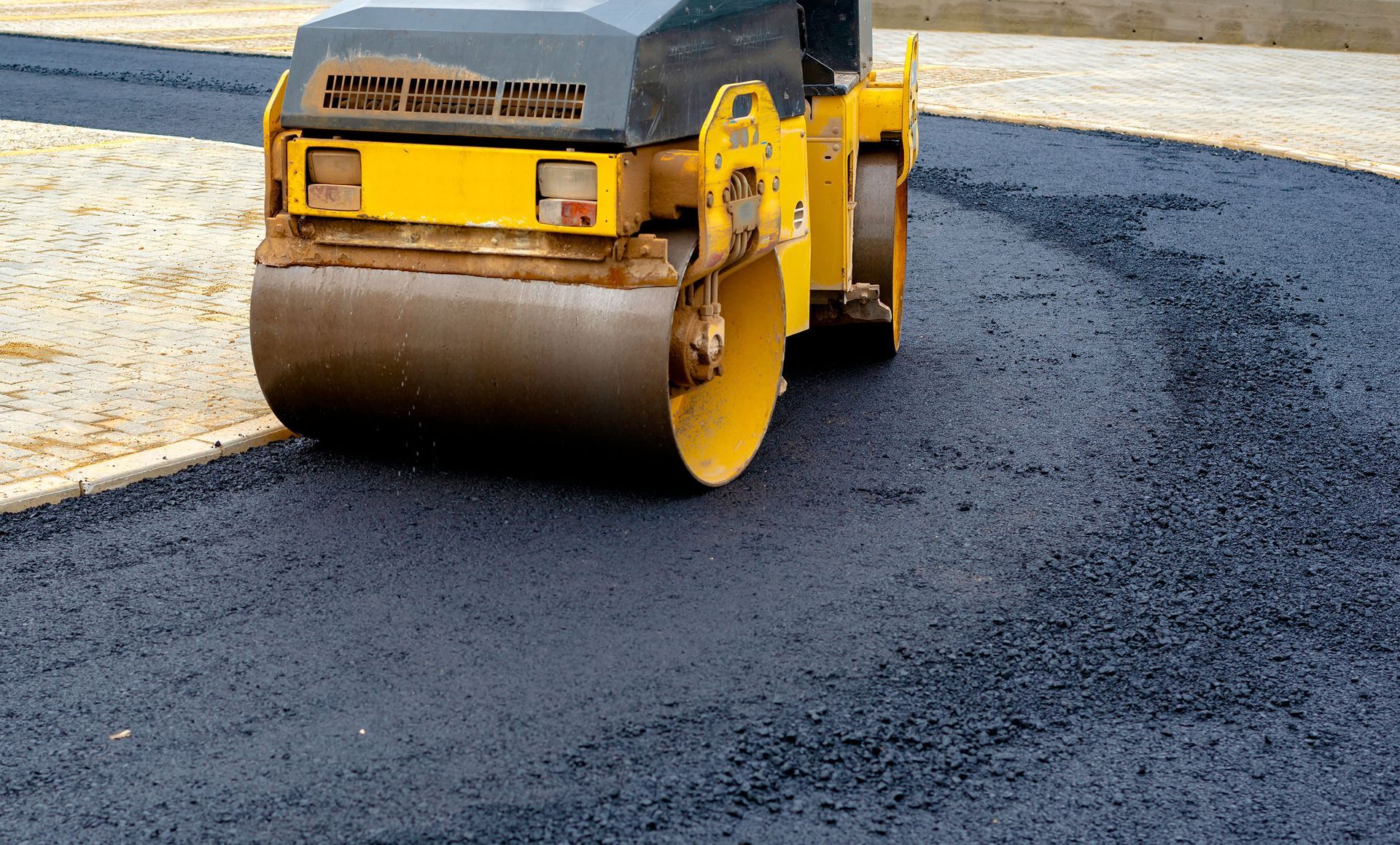 Fresh hot-mix asphalt being machine-laid by a paving crew
